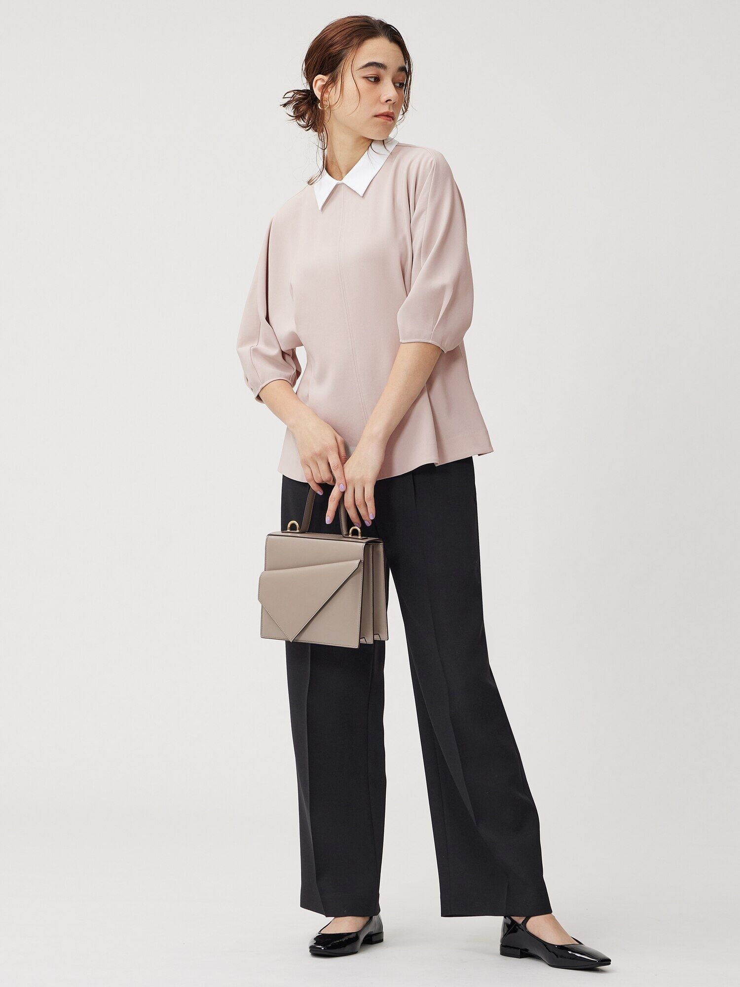 ピンクベージュのトップスと黒パンツのコーデ