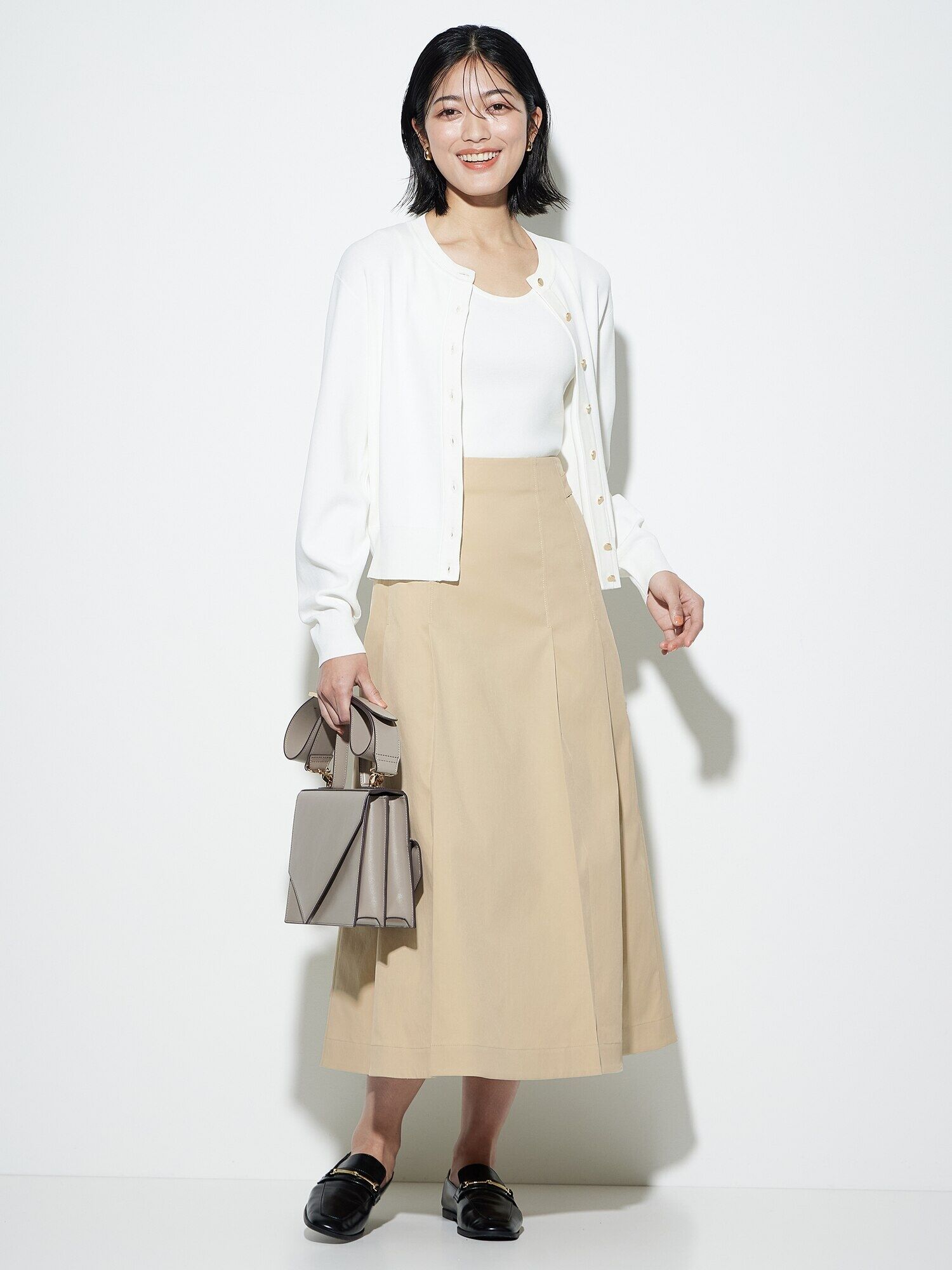 ベージュのスカートに白のニットカーデを合わせたコーデ